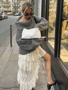 Close-up of a minimalist white cloud clutch bag with black REFY logo in a street setting