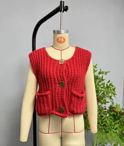 Detail of red cable knit vest featuring decorative golden buttons and square pockets