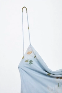 Detail of light blue floral dress showing slim shoulder straps and draped neckline