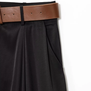 Détails du pantalon large noir avec ceinture en cuir marron et finitions plissées