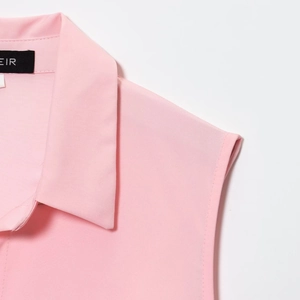 Detail shot of pink sleeveless shirt collar showing refined fabric and EIR brand neck label