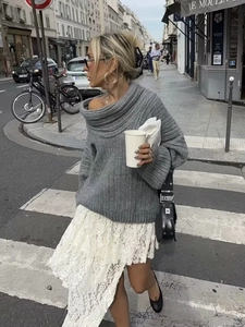 Close-up of grey off-shoulder knit sweater with thick texture and relaxed fit