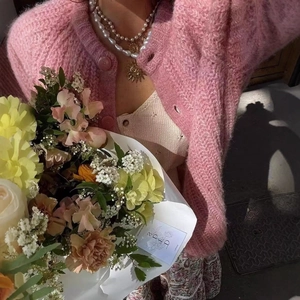 Pink mohair knit cardigan styled with pearls and a fresh flower bouquet in soft light