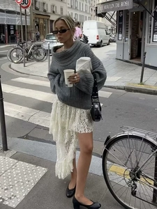 Outdoor street style shot of grey oversized ribbed knit off-shoulder sweater and lace skirt