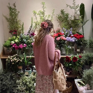 Chic pink knit cardigan and floral skirt outfit with a flower hair tie in a garden setting
