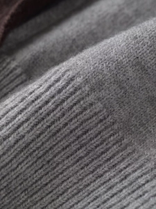 Detailed macro view of soft gray knitted fabric texture with fine wool blend ribbing