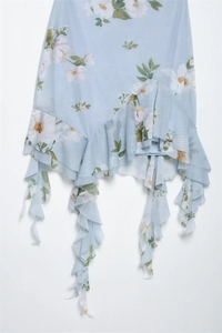 Detailed view of light blue floral dress with asymmetric layered ruffles and chiffon fabric