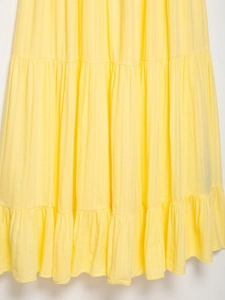 Dettaglio di un abito giallo a strati con texture verticale e balze plissettate