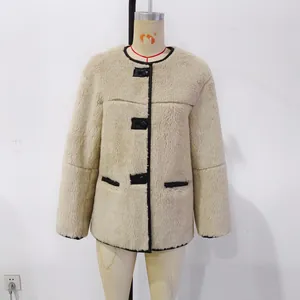 Detail of beige faux fur coat with black contrast trim and large round buttons