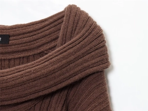 Close-up detail of dark brown ribbed knit sweater with shoulder fold and premium texture