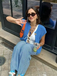Women sleeveless blue knit vest with white striped pants and an orange handbag outfit