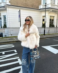 Dettaglio del cappotto in ecopelliccia bianca abbinato a jeans blu a gamba larga
