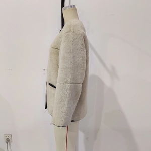 Detail shot of a plush cream faux fur jacket texture with black zipper accents