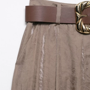 Détail du pantalon large en satin au fini métallique et boucle de ceinture dorée en spirale