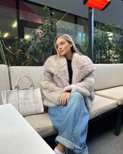 Dettaglio cappotto in pelliccia sintetica beige con ampio bavero e consistenza morbida