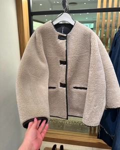 Detail of beige faux fur jacket with black leather trim and decorative buttons