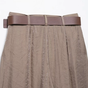 Détail du pantalon large kaki en satin plissé avec une ceinture marron élégante