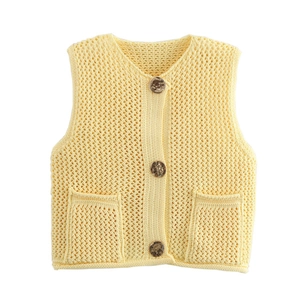 Close-up of chunky knit pattern and wood-textured buttons on yellow sleeveless top