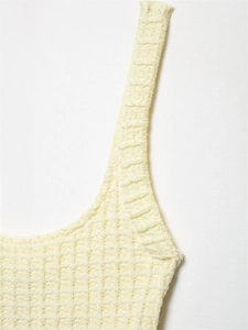 Makro-Detail der Waffelstruktur und feinen Nähte an einem cremefarbenen Strickkleid