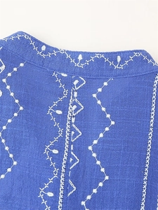Gros plan détaillé sur la broderie géométrique blanche sur un tissu bleu marine en lin