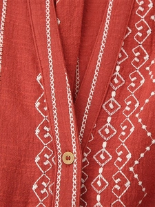 Détail d'une chemise en coton et lin brique avec broderie géométrique et bouton en bois