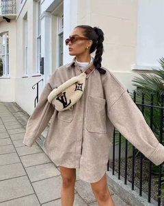 Detail of beige oversized wool jacket with large pockets and white sherpa waist bag