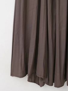 Gros plan détaillé de l'ourlet de robe en satin plissé marron foncé avec texture