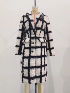 Macro detail of black and white checkered long coat showing warm plush faux fur texture