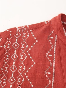 Détails de broderie sur un chemisier en coton et lin rouille aux motifs bohèmes