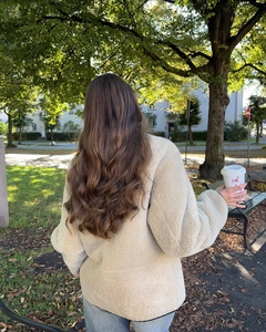 Detail showing the thick beige sherpa fleece texture and back cut of the oversized jacket