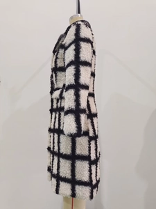 Detail of black and white checkered long coat with thick plush texture and wooly fabric