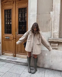 Detail of a beige wool-mix shacket with dark beige knitwear and green boots