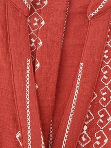 Détail de la broderie géométrique blanche sur le tissu en lin de la chemise rouille