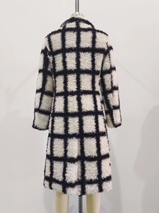 Detail view of the back of a black and white plaid long plush coat with textured wool fabric