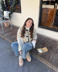 Detail of beige shearling snow boots paired with wool jacket and denim jeans