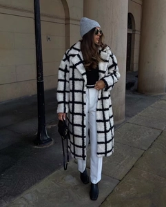 Detail view of a long checkered teddy coat with soft plush texture and lapel collar