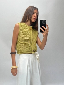 Grass green knit vest with amber buttons and front pockets in a short cut sleeveless style