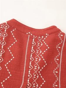 Détail de la broderie du col en V et de la texture en lin rouge brique de la chemise d'été