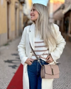 Detail of a white fuzzy long coat paired with a pink quilted leather crossbody bag