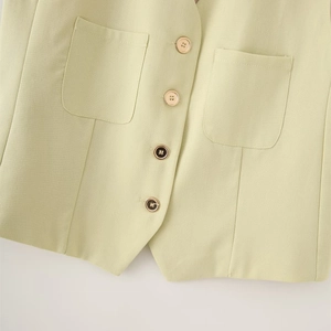 Close-up of light green linen vest featuring textured fabric and contrasting buttons