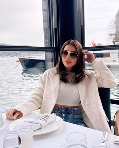 Detail of white tweed long coat with gold-rimmed sunglasses in outdoor setting
