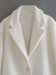 Close-up of white plush coat showing teddy fleece texture and classic notched lapel