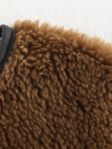 Close-up of brown sherpa fleece fabric with premium black faux leather trim texture