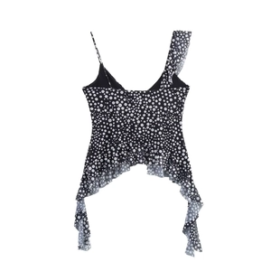 Detailed view of women's black and white polka dot top with asymmetrical ruffled hem