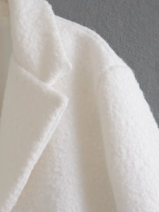 Detail of soft white boucle fabric texture and stitching on the collar of a long coat