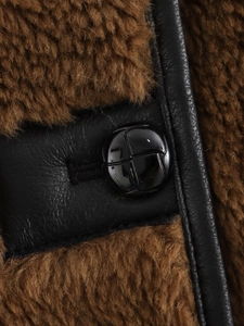 Detail of faux shearling jacket with black leather trim and polished round button