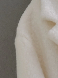 Detail of soft cream faux fur texture and precise stitching on the white long coat