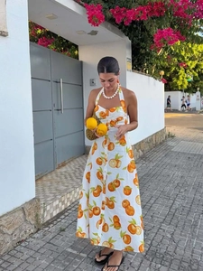 Outdoor street shot of a white halter maxi dress with vibrant orange citrus prints