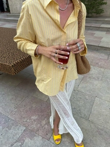 Camicia chic a righe gialle con pantaloni all'uncinetto bianchi e borsa in paglia