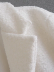 Close-up of soft white sherpa fleece fabric texture on long coat with overlapping collar